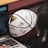 A signed basketball rests against a laptop on a table. A person's hand is visible, possibly using the laptop, and a microphone can be seen close by, suggesting an interview or commentary setting.